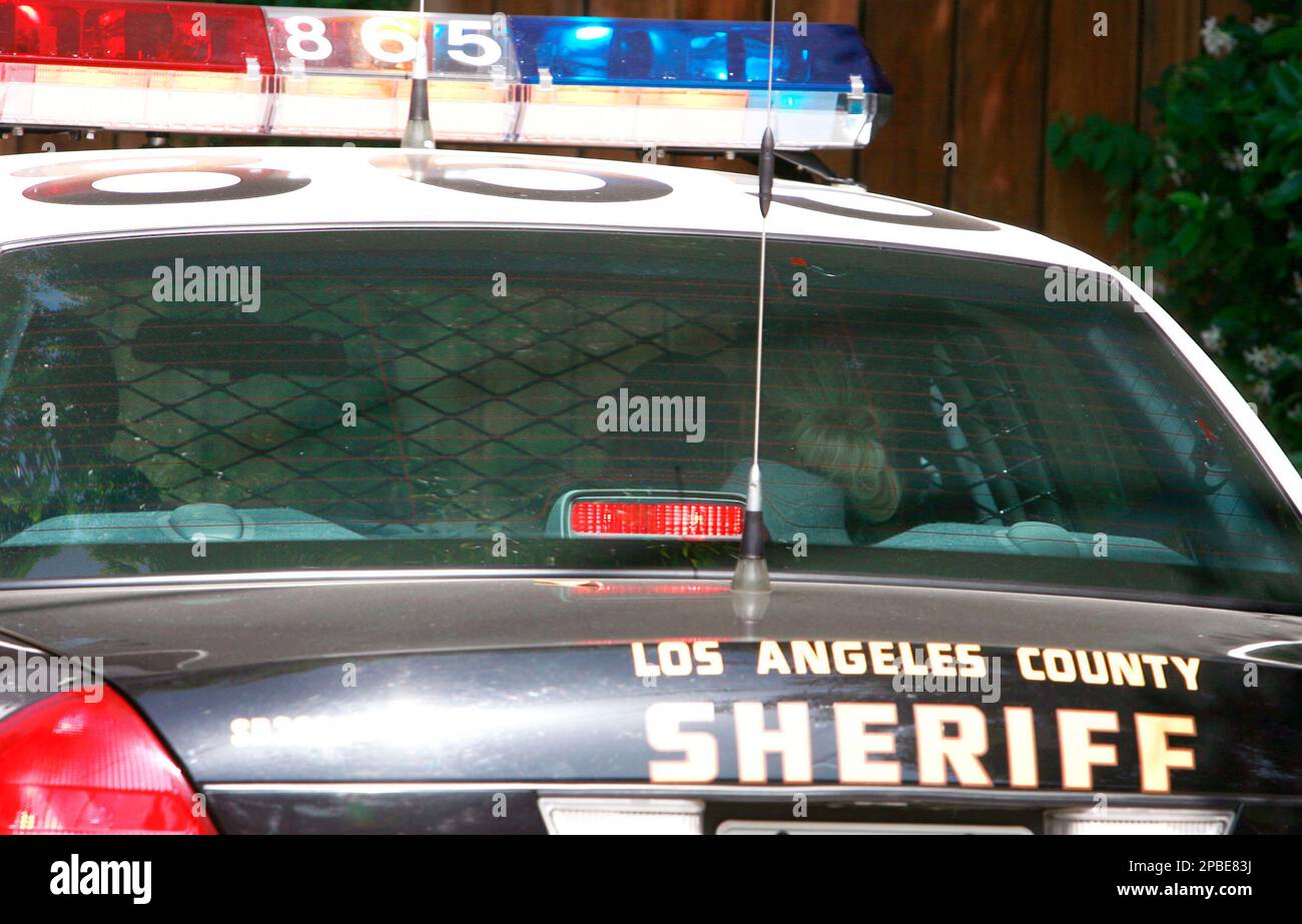 Paris Hilton, right, is transported in the back of a police car from