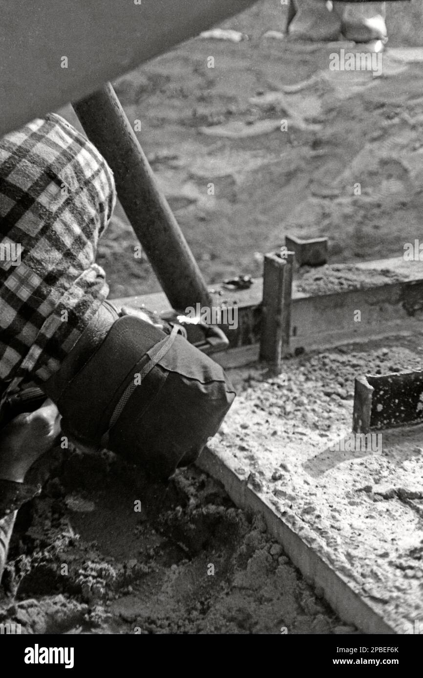 Vintage or retro monochrome photo of a welder, welding a metal pipe to a steel frame. 1971 Stock Photo