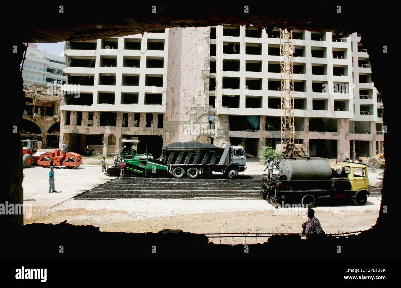Workmen finish filling in the crater, seen through a hole in a bomb ...