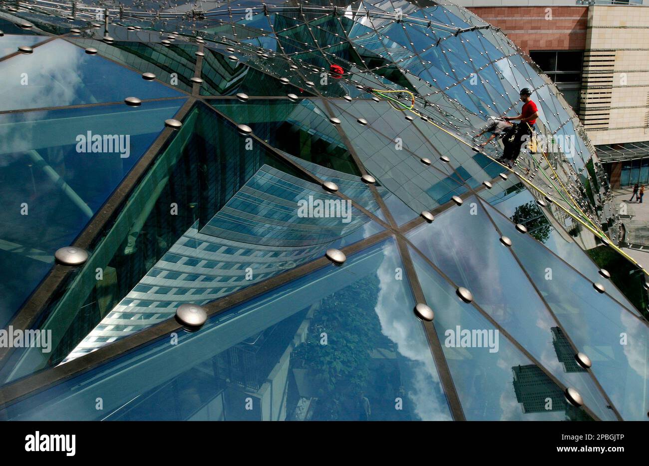 Mountain climbers earn money washing the curved glass roof of Warsaw's