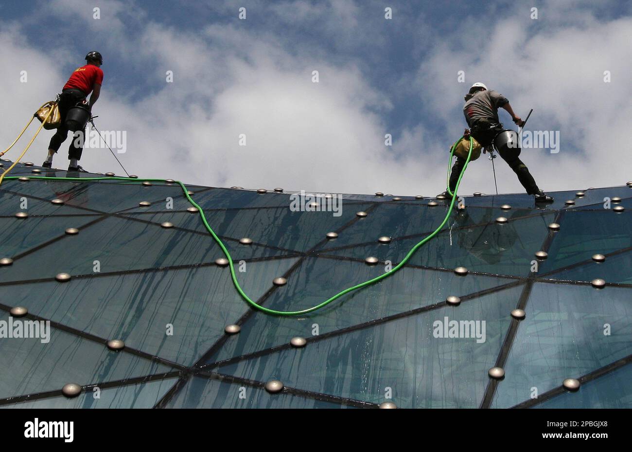 Mountain climbers earn money washing the curved glass roof of Warsaw's