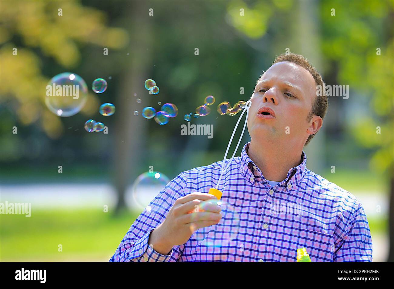 Man blowing bubbles on sunny spring day in park Stock Photo
