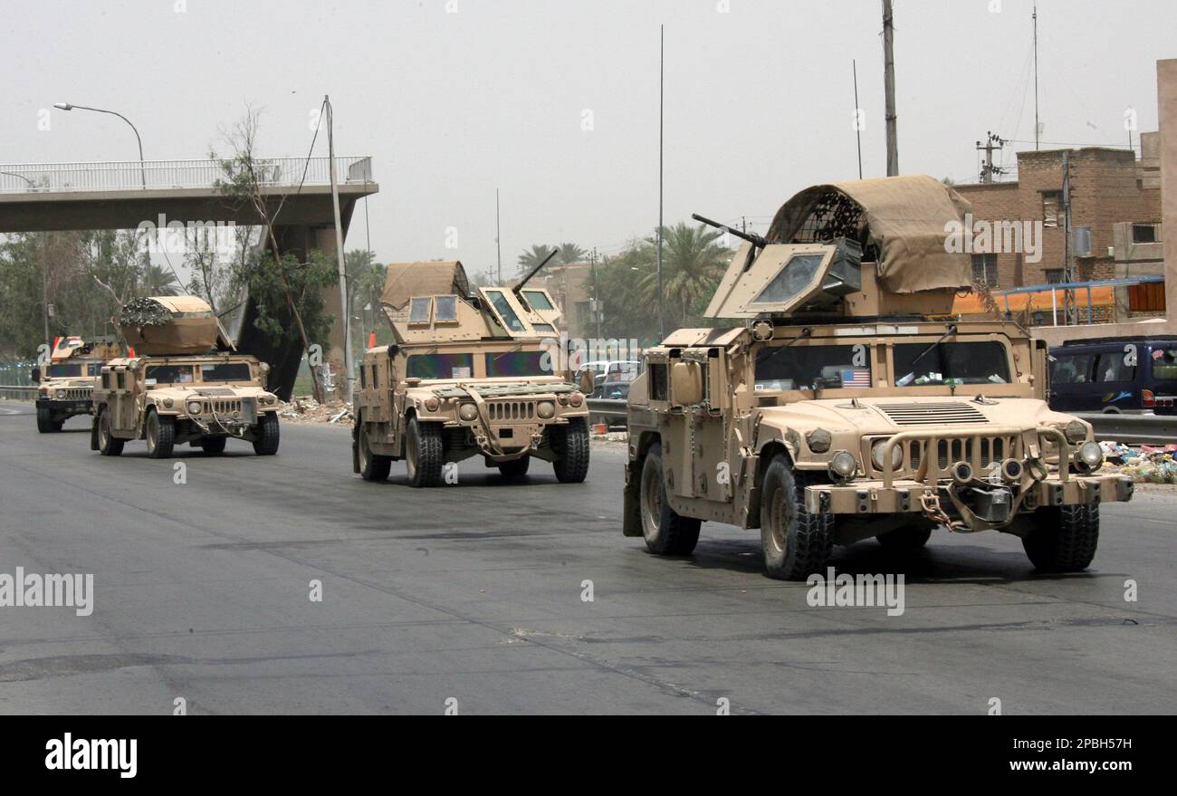 A U.S. military convoy moves past a scene of a sniper attack in ...