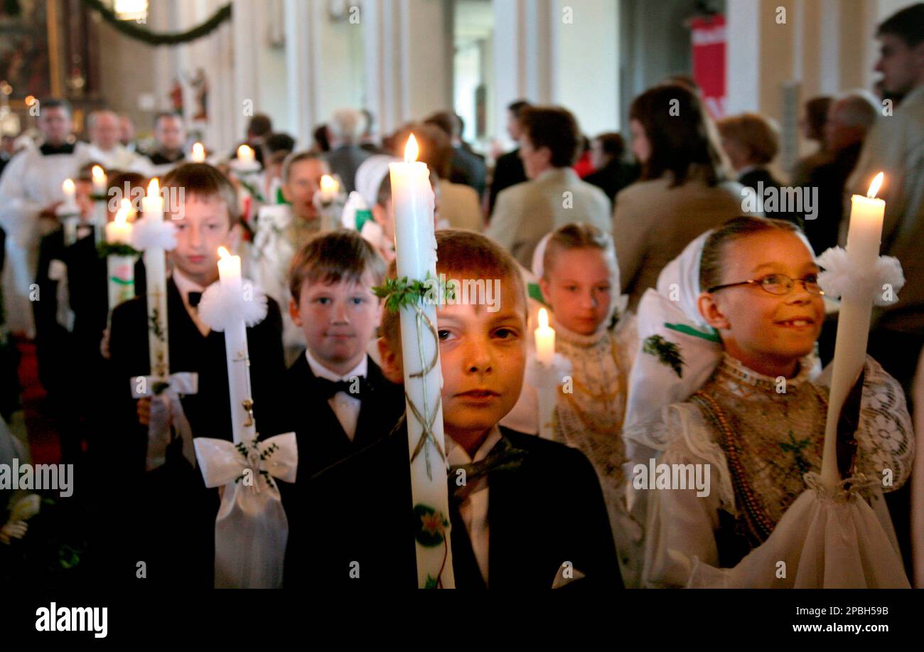 Kinder tragen Kerzen aus der Kirche am Sonntag, 13. Mai 2007, in Crostwitz zur Erstkommunion. 16 Kinder im Alter von 8 und 9 Jahren, die Maedchen dabei in der Tracht der Druschka