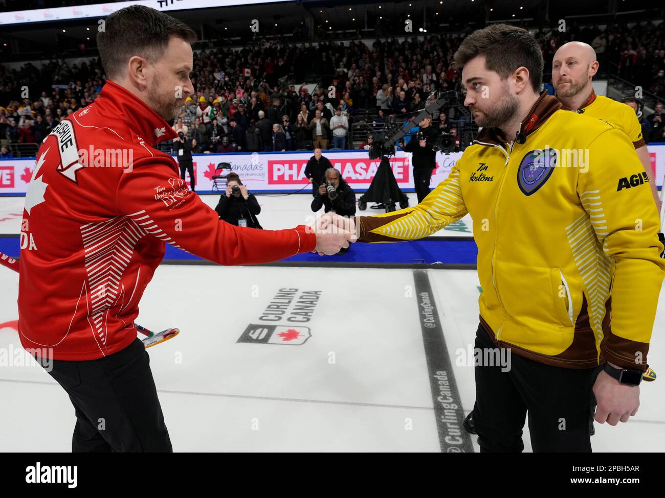 Team Canada skip Brad Gushue, left, shakes hands with Team Manitoba skip Matt Dunstone after winning the finals of the Tim Hortons Brier curling event in London, Ontario, Sunday, March 12, 2023