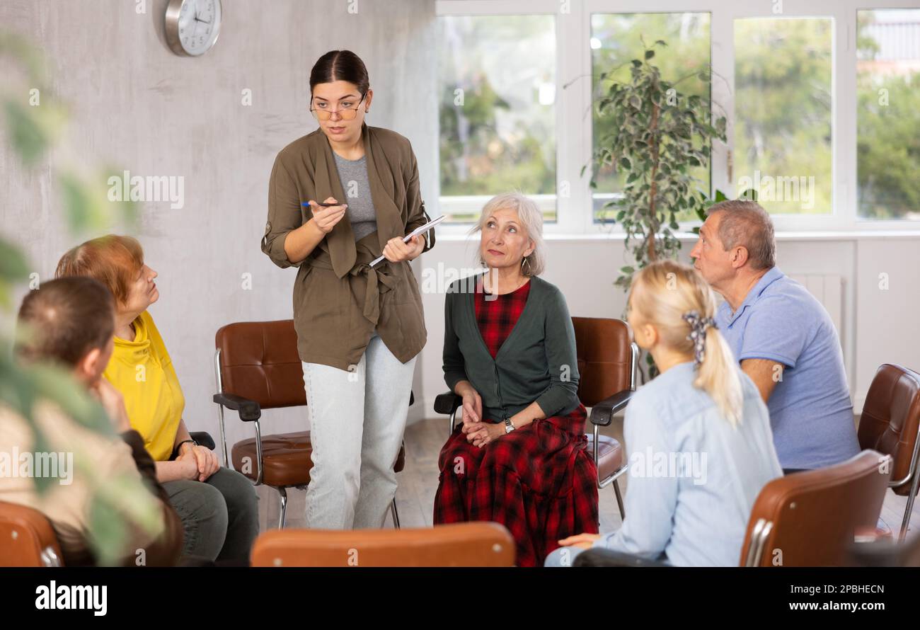 Young girl conducting language club for group of older adults Stock Photo