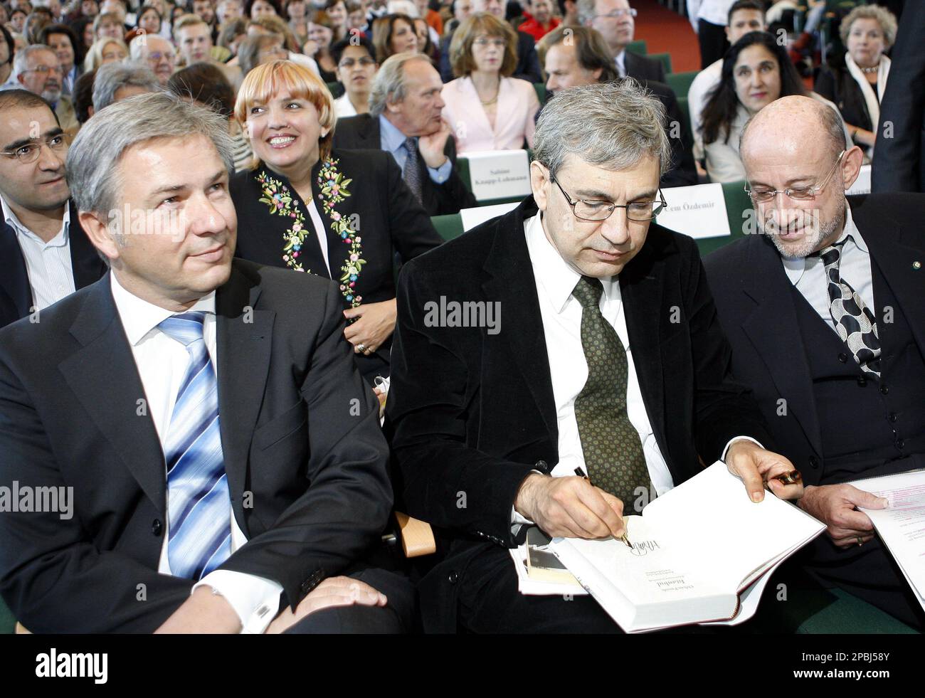 Orhan Pamuk, Turkish writer and Nobel prize for literature laureate,  center, signs a book for the First Vice Chairman of the Free University of  Berlin, Klaus W. Hempfer, right, while Berlin mayor