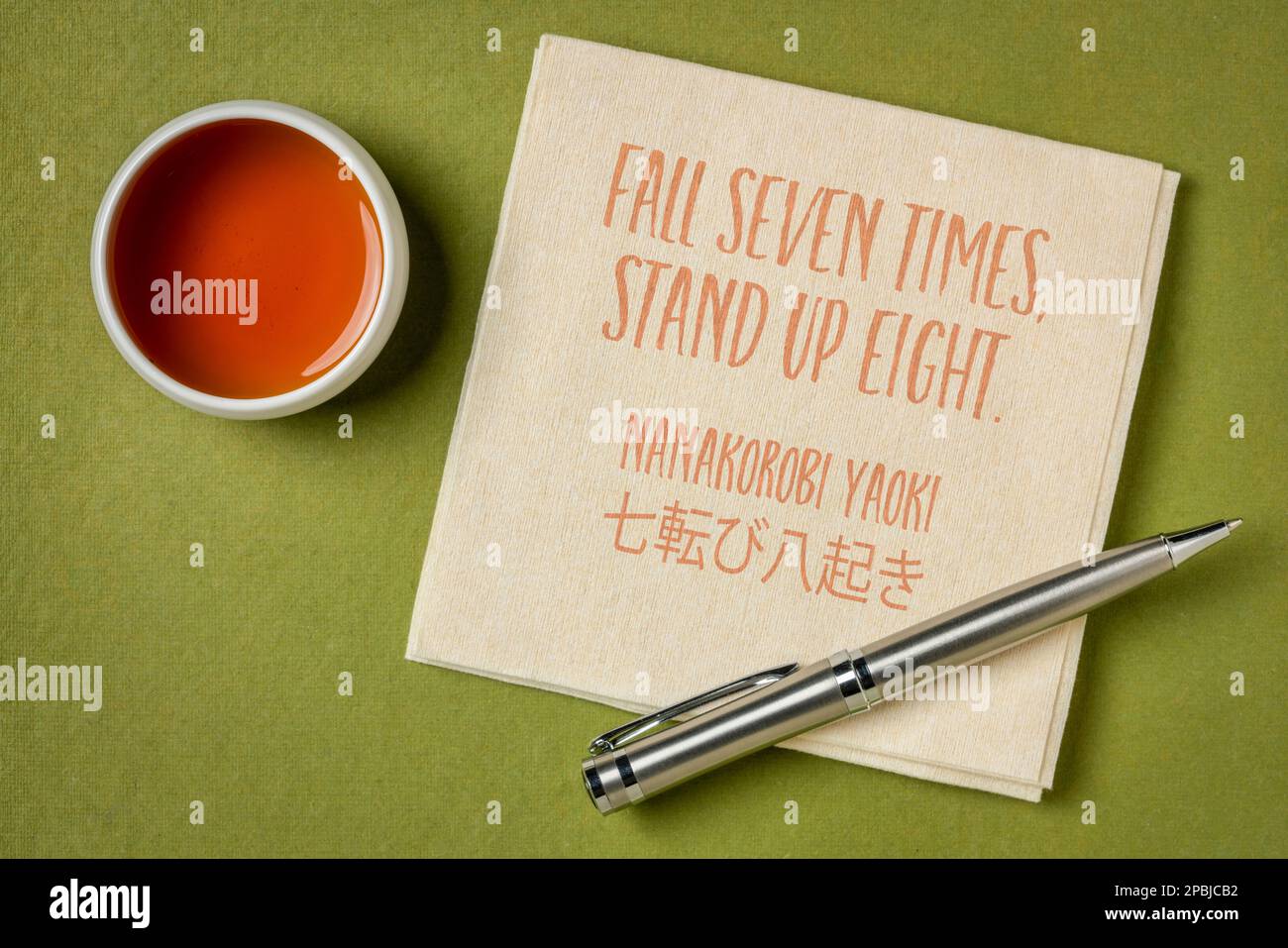 Fall seven times, stand up eight. Japanese proverb on napkin with a cup of tea. Determination and persistence concept. Stock Photo