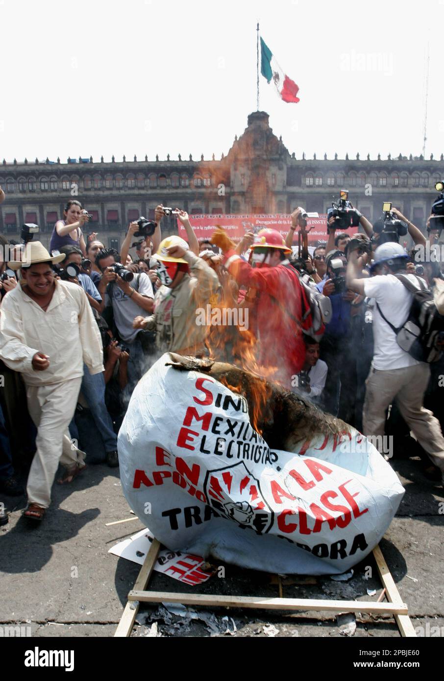 Workers from the Mexican Electrician Union burn a paper balloon that