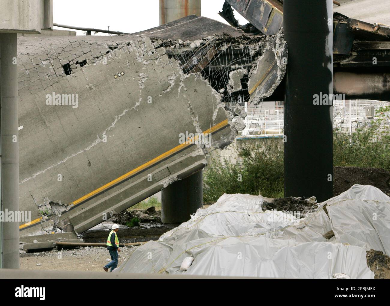 A CalTrans worker walks beneath a crumbled section of freeway ramp ...