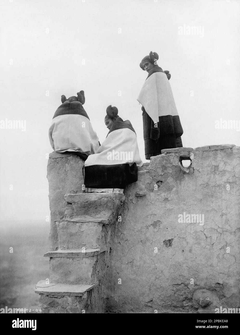 1906 , NEW MEXICO , USA : Three Hopi women at top of adobe steps, New Mexico . Photo by celebrated  american photographer  EDWARD S. CURTIS ( 1868 - 1952 )  - HISTORY - foto storiche - foto storica  - HOPI  Indians - INDIANI D' AMERICA - PELLEROSSA - natives americans  - Indians of North America -  WOMAN - WOMEN - DONNA - DONNE - chignon - mantle - mantello - poncho -  INDIANO - portrait - ritratto - pellerossa  - foto pittorialista - pictorialist photograph  -    ----  Archivio GBB Stock Photo
