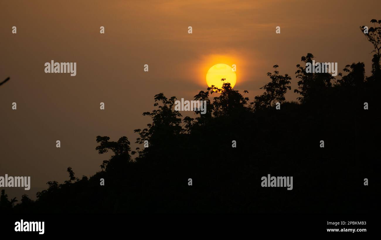Beautiful sunrise view. Clouds on one side and the sun rising over the mountains on the other. Hilly region of Bangladesh. Photo taken from Meghbari, Stock Photo