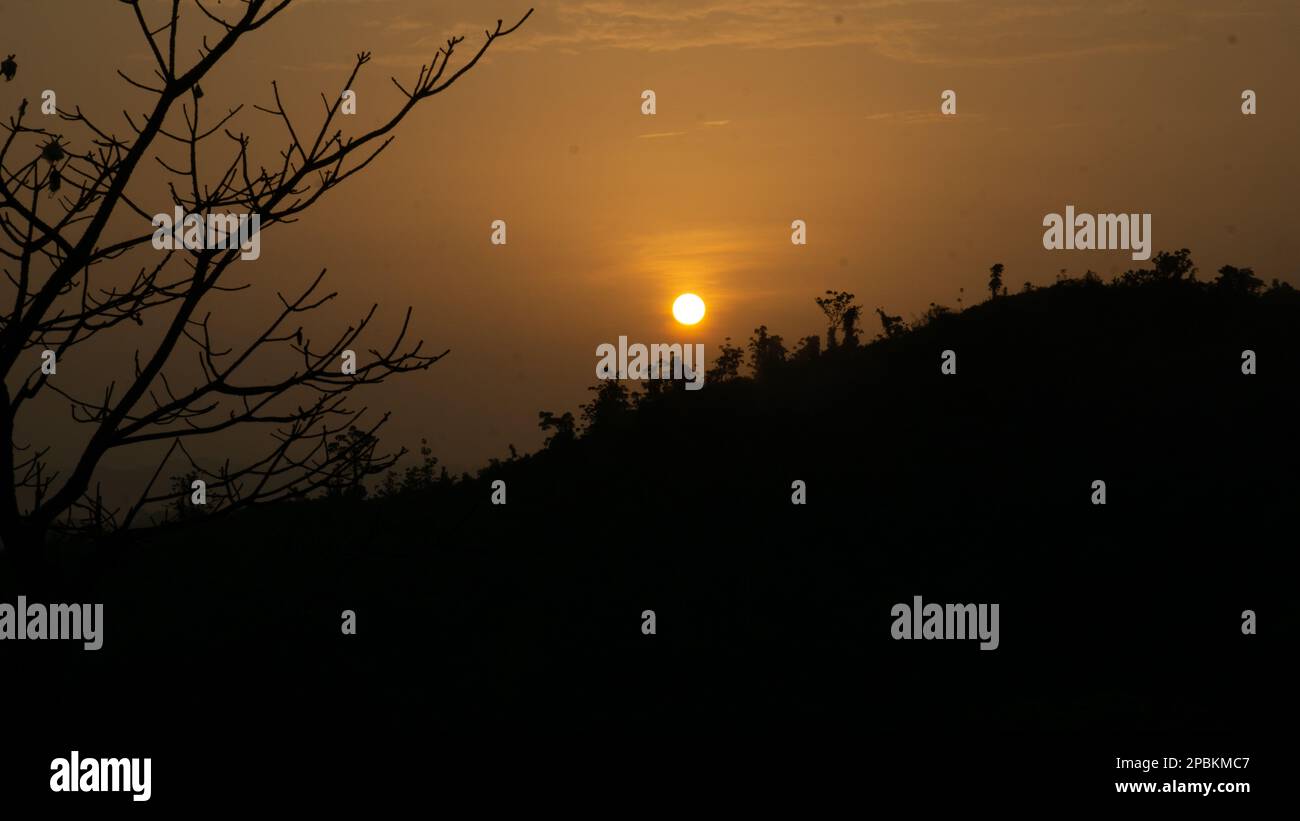 Beautiful sunrise view. Clouds on one side and the sun rising over the mountains on the other. Hilly region of Bangladesh. Photo taken from Meghbari, Stock Photo