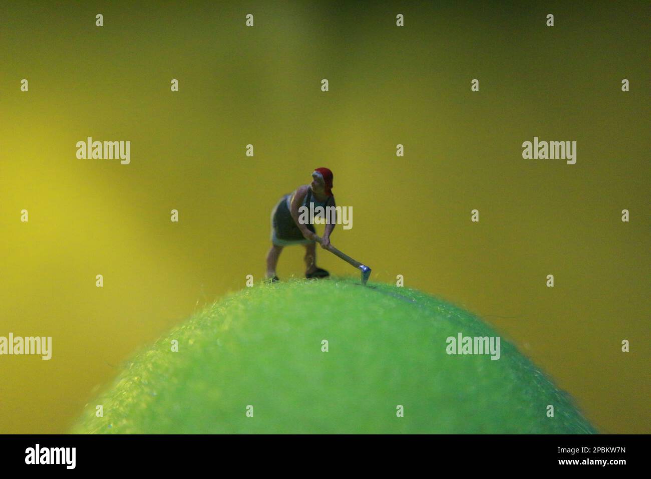 miniature figure of a female farmer working the land with a sunrise background. Stock Photo