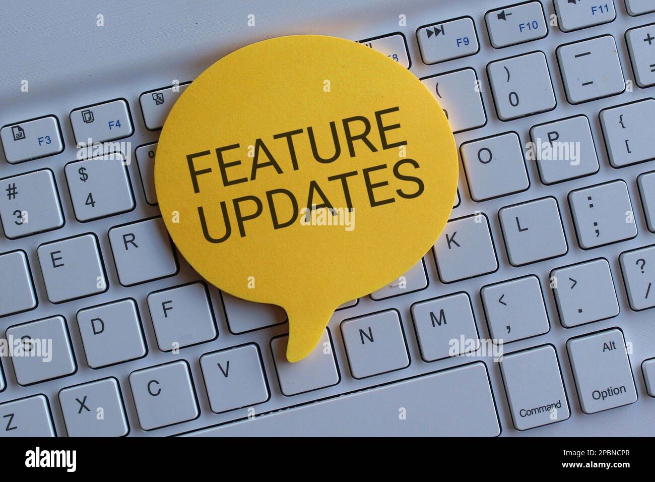 Top view image of keyboard and speech bubble with text FEATURE UPDATES. Technology concept Stock Photo