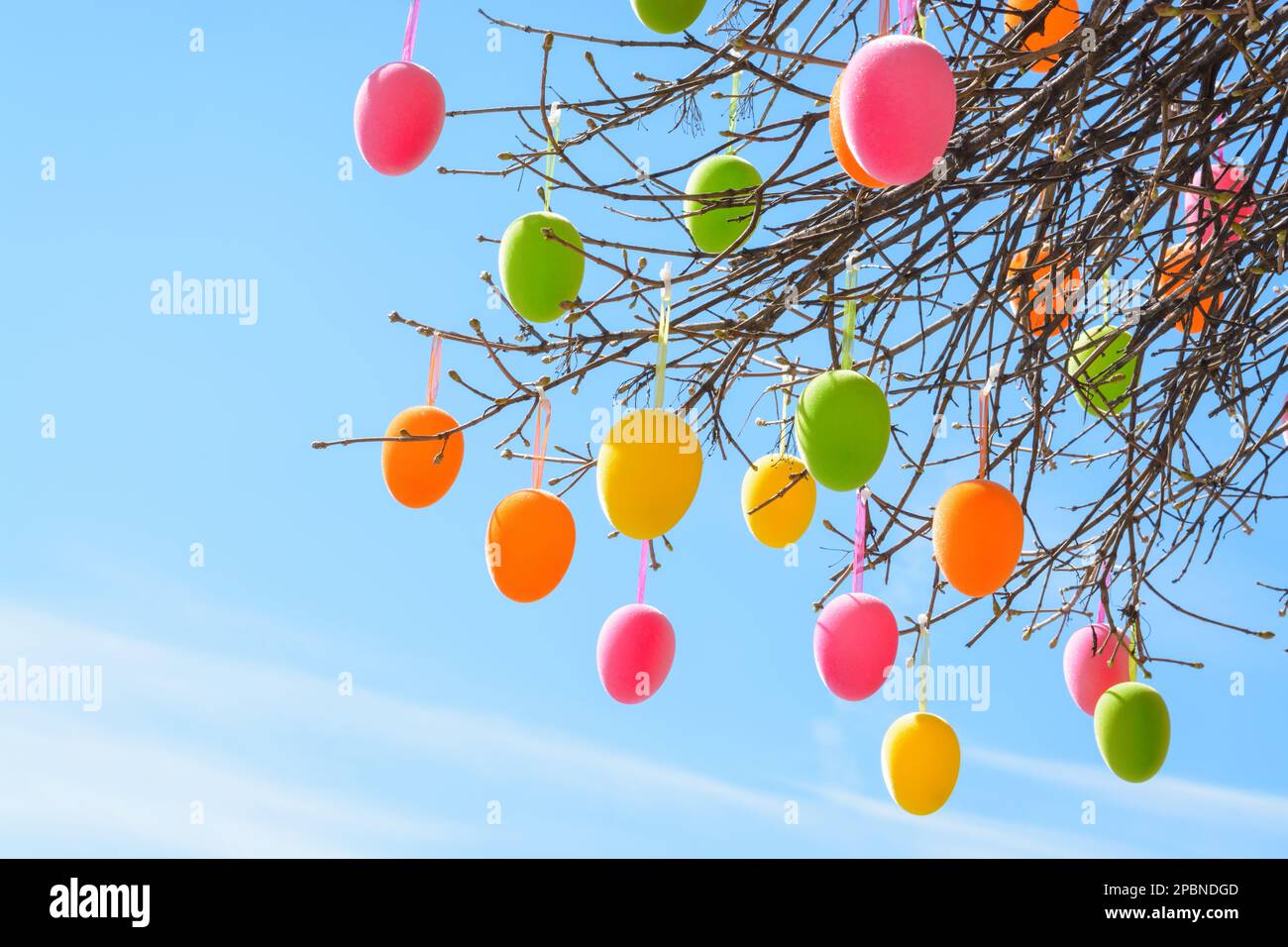 Multi-colored Easter eggs against the background of a light blue sky, horizontal format Stock Photo