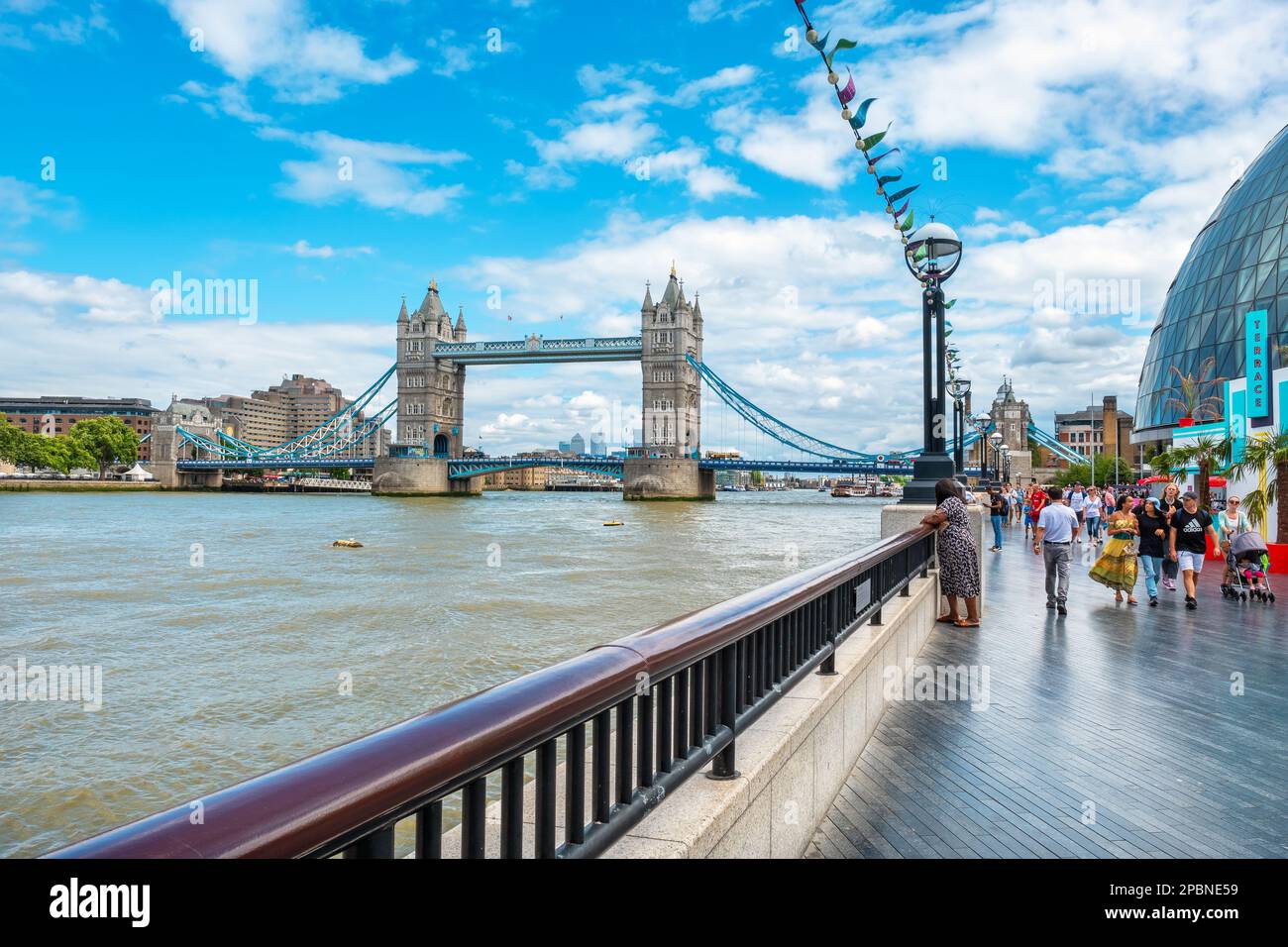 Crowded Thames southbank promenade with Tower Bridge view. London, England, UK Stock Photo