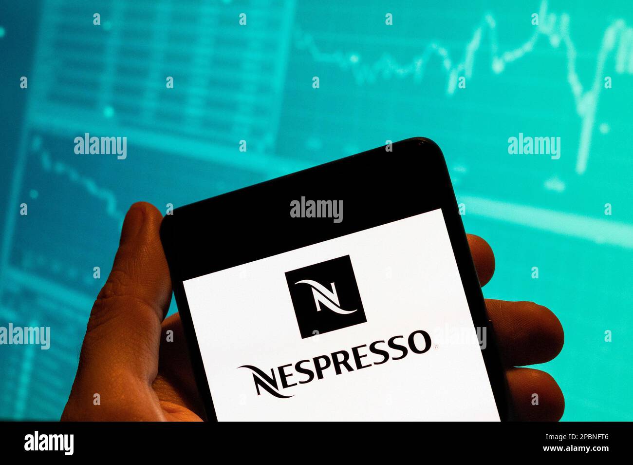 China. 15th Feb, 2023. In this photo illustration, the Swiss high-end and world leader in coffee capsules brand store Nespresso logo is seen displayed on a smartphone with an economic stock exchange index graph in the background. (Credit Image: © Budrul Chukrut/SOPA Images via ZUMA Press Wire) EDITORIAL USAGE ONLY! Not for Commercial USAGE! Stock Photo