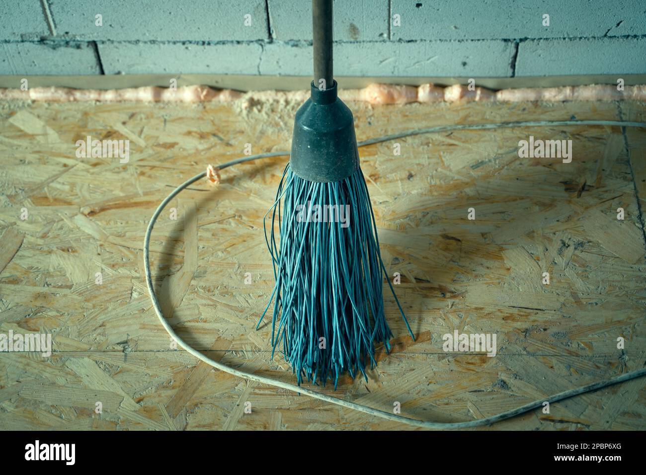 Plastic blue round broom closeup on the floor from the osb plate