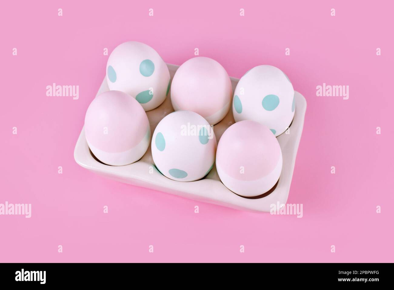 Pastel colored painted Easter eggs in egg tray on pink background Stock Photo