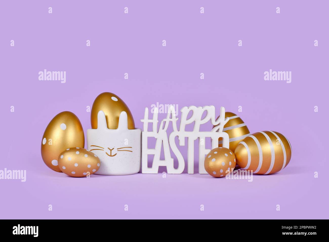 Golden easter eggs and text Happy easter on violet background Stock Photo