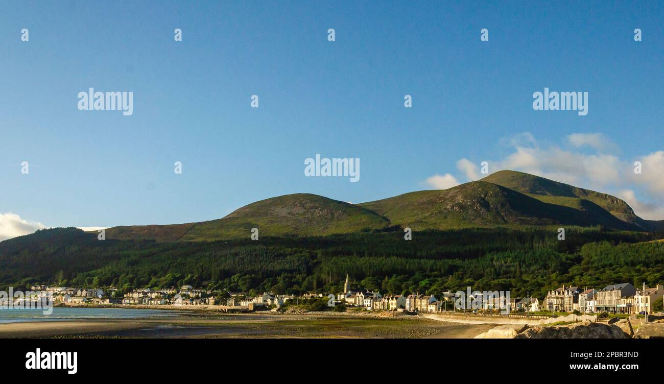 The Mourne Mountains viewed from the beach at Newcastle County Down, with blue sky and seafront
