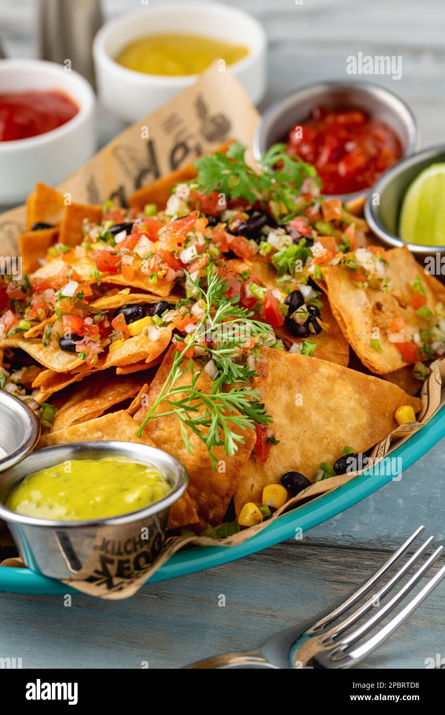Traditional mexican food nachos with various sauces on wooden table Stock Photo