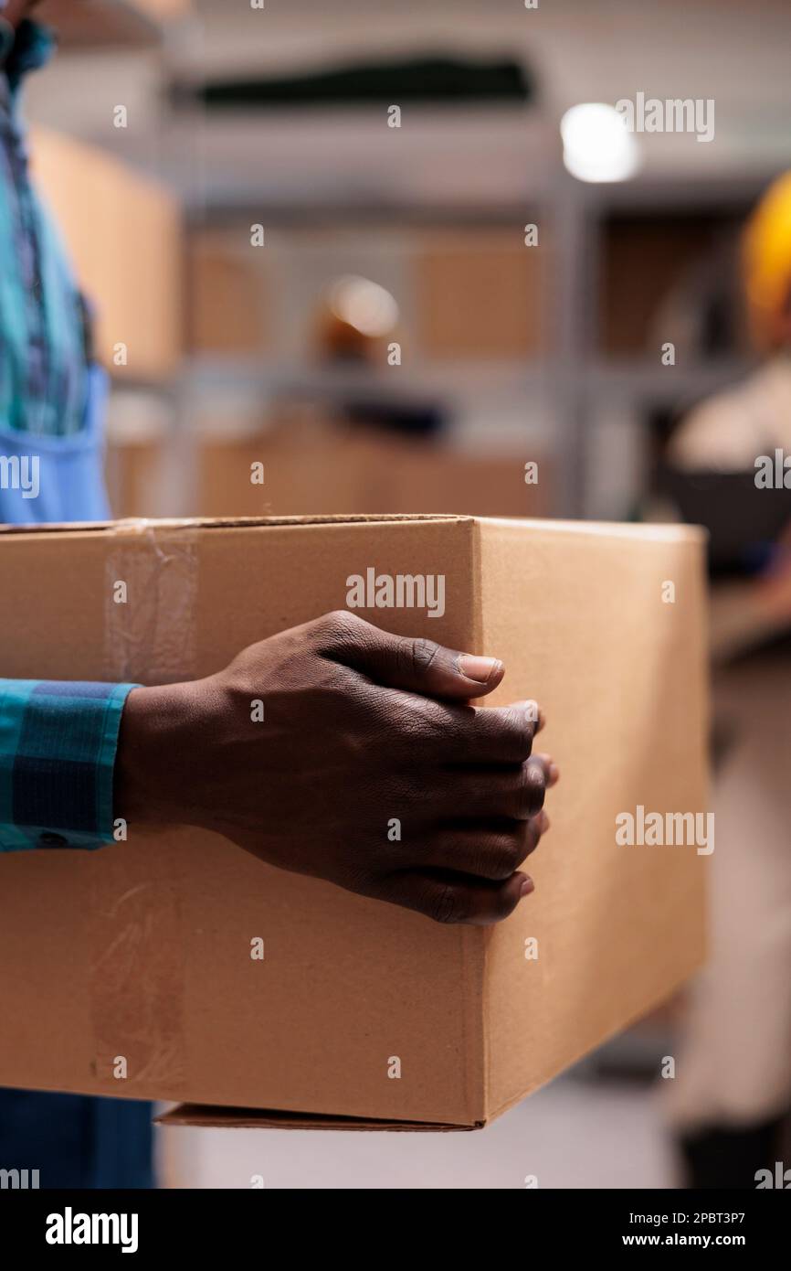 Industrial warehouse employee holding cardboard package ready for