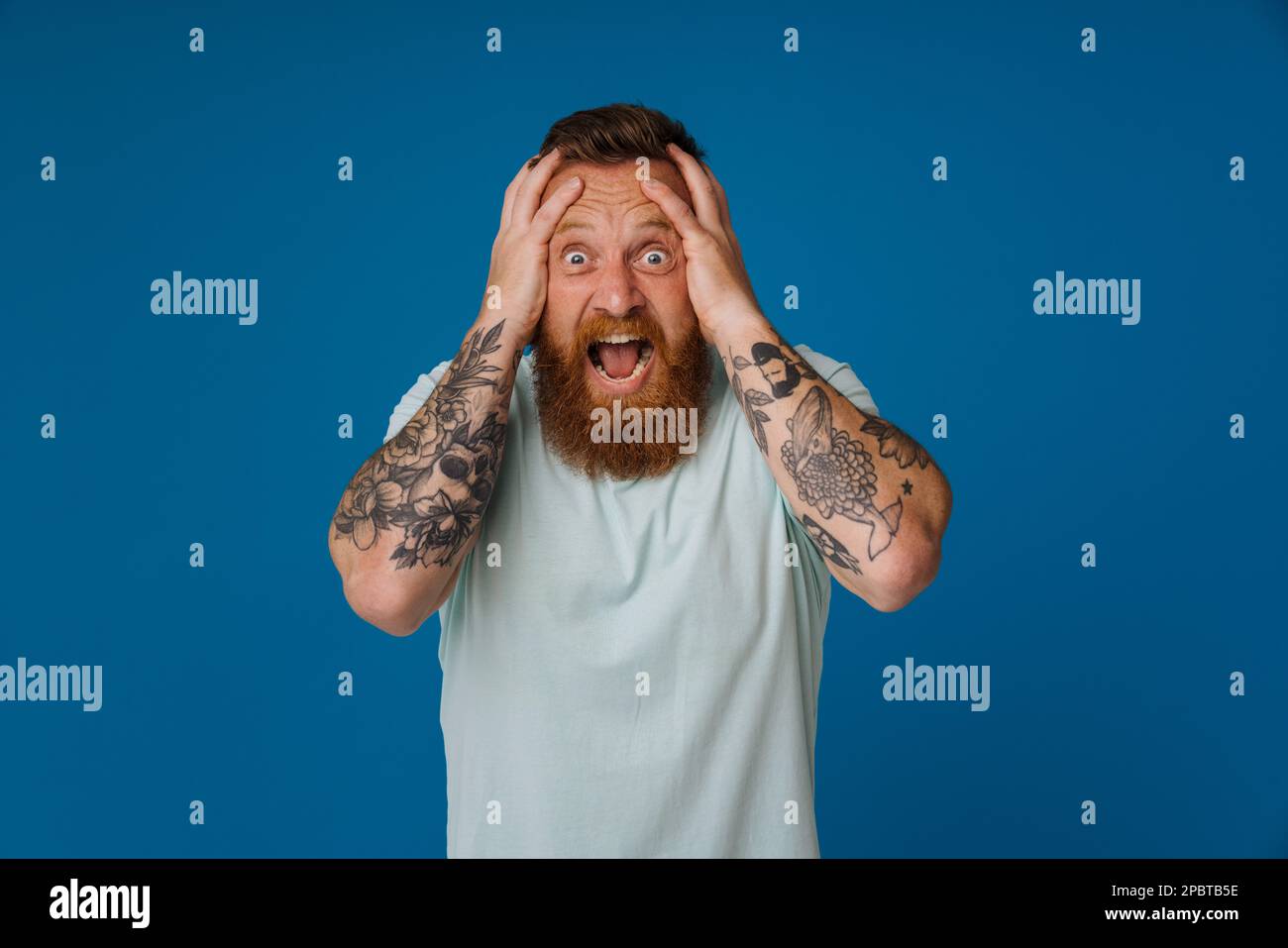 Adult bearded tattooed handsome stylish stressed man with opened mouth ...