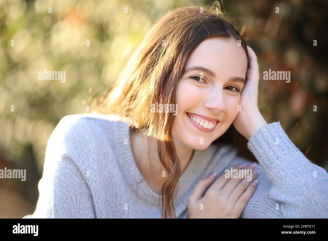 Portrait of a happy woman looking at camera sitting in a park Stock Photo
