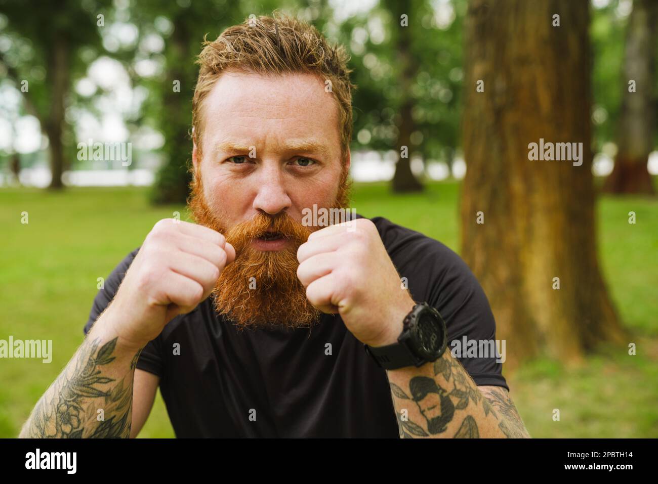 Ginger bearded man doing exercise during workout in park outdoors Stock Photo
