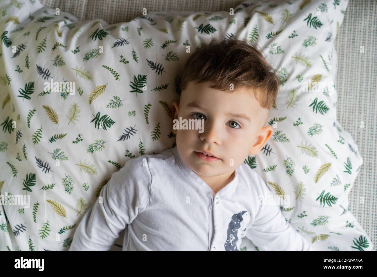 Happy little child boy in pajamas, in bed in the bedroom with to Stock