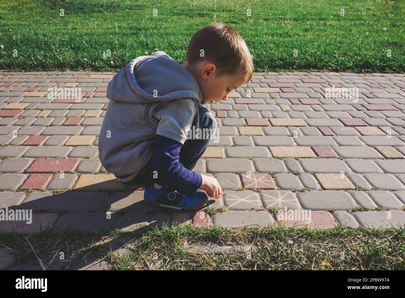 Boy using sidewalk chalk on a walkway Stock Photo - Alamy