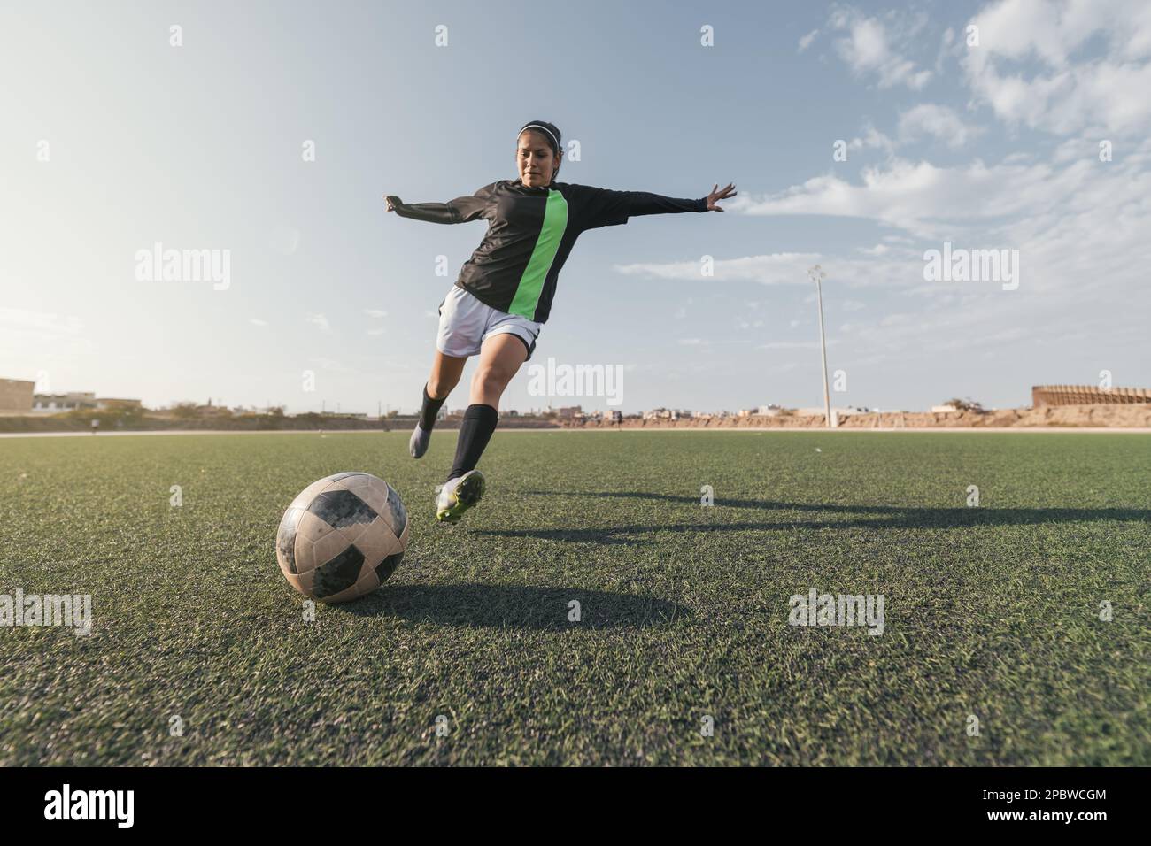 Young female soccer player kicking ball in a stadium Stock Photo - Alamy