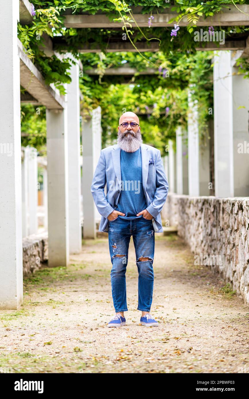 man posing standing with his hands in his pockets in a city park. Stock Photo
