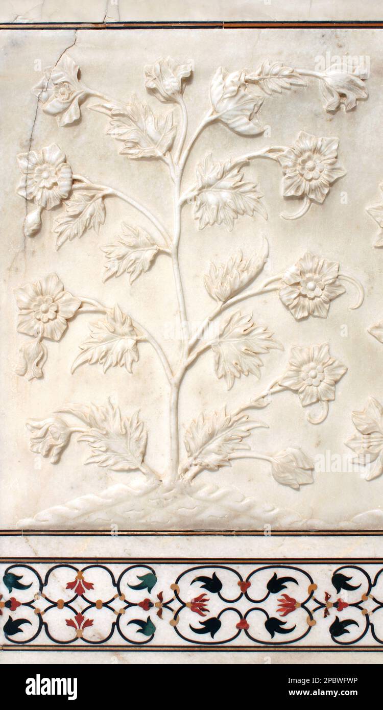 Ancient carved bas-relief with flowers on marble. Beautiful ornament with carved flower on the wall of the famous mausoleum Taj Mahal, India. UNESCO w Stock Photo