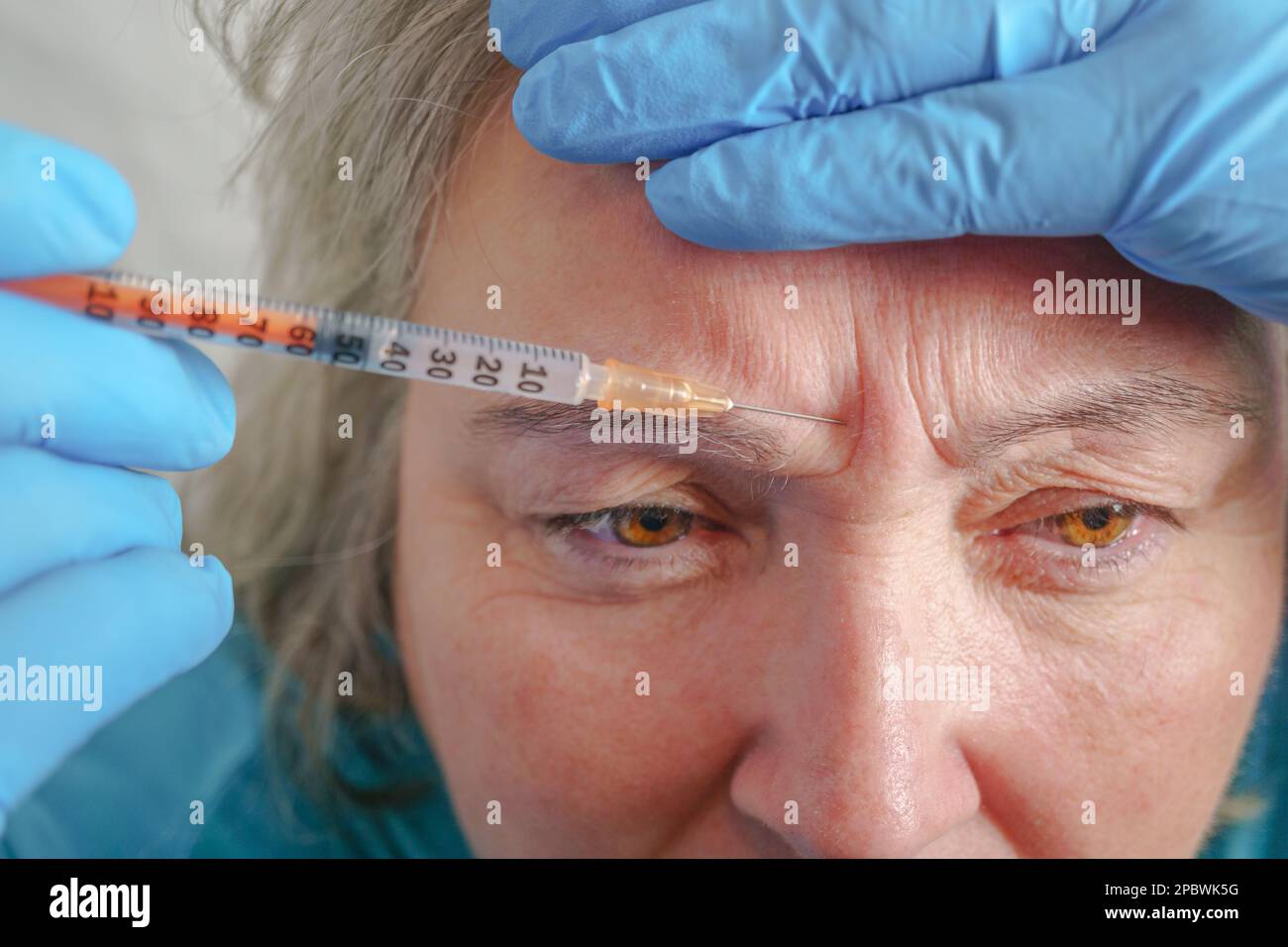 Aged lady having botox injecting procedure. Cosmetic treatment Stock Photo