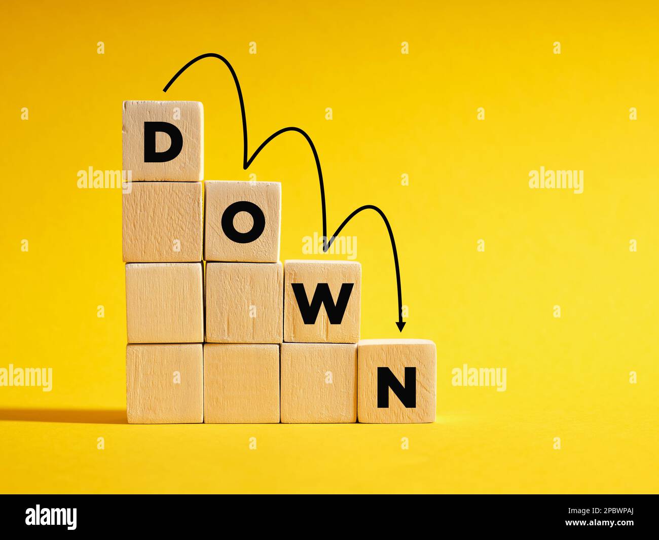 The word Down on descending step stairs of wooden cubes. Business or economic run down, recession, decrease, profit loss or career decline concepts. Stock Photo