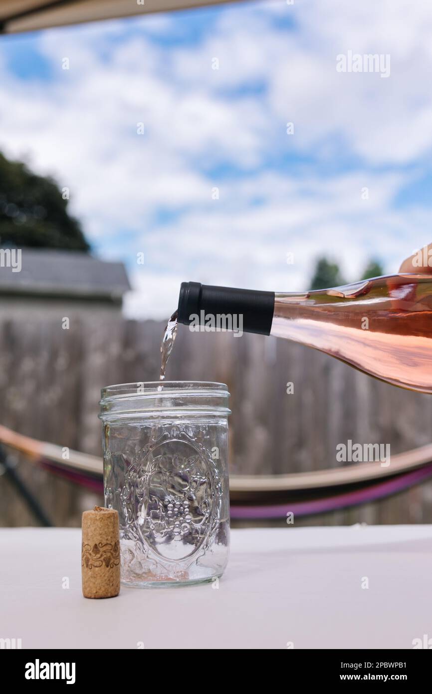 Beautiful blue sky with puffy clouds and rose wine being poured Stock Photo