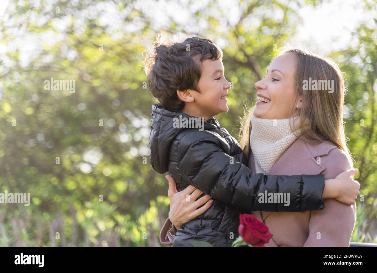 Woman and son laughing. Red rose in mother day. Outside Stock Photo