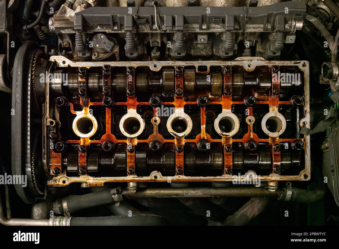 Opened oily car engine cylinder head. Top view, exposed cam shaft, no