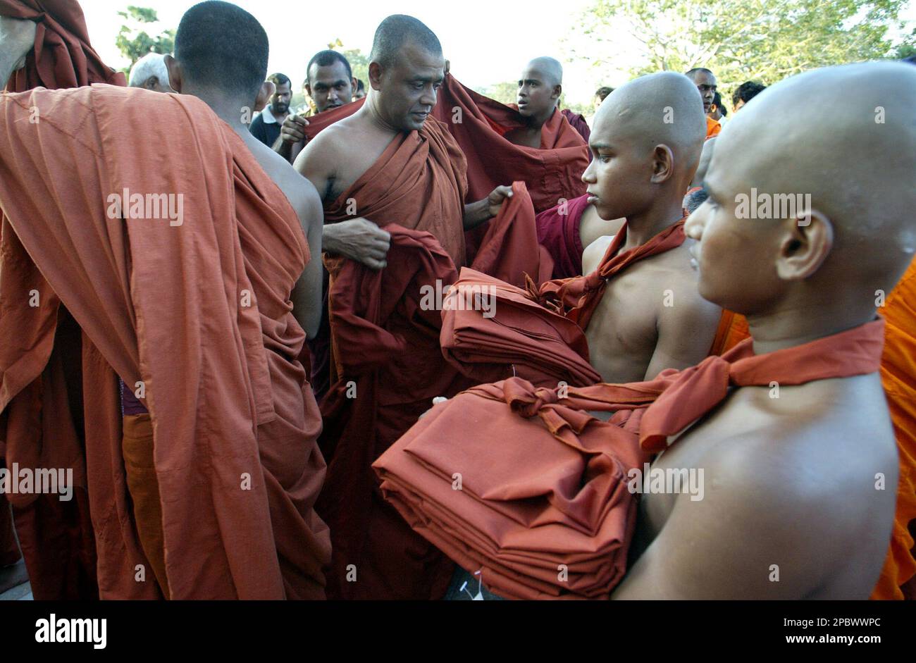 Buddhist monks help young novice monks with tying their robe during a ceremony to ordain boys to