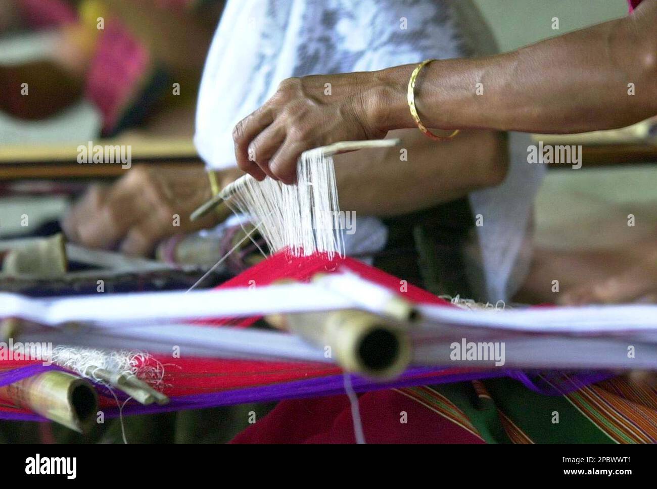 Bangladeshi tribal women weave on a traditional handloom at an exhibition by Prabartana in Dhaka