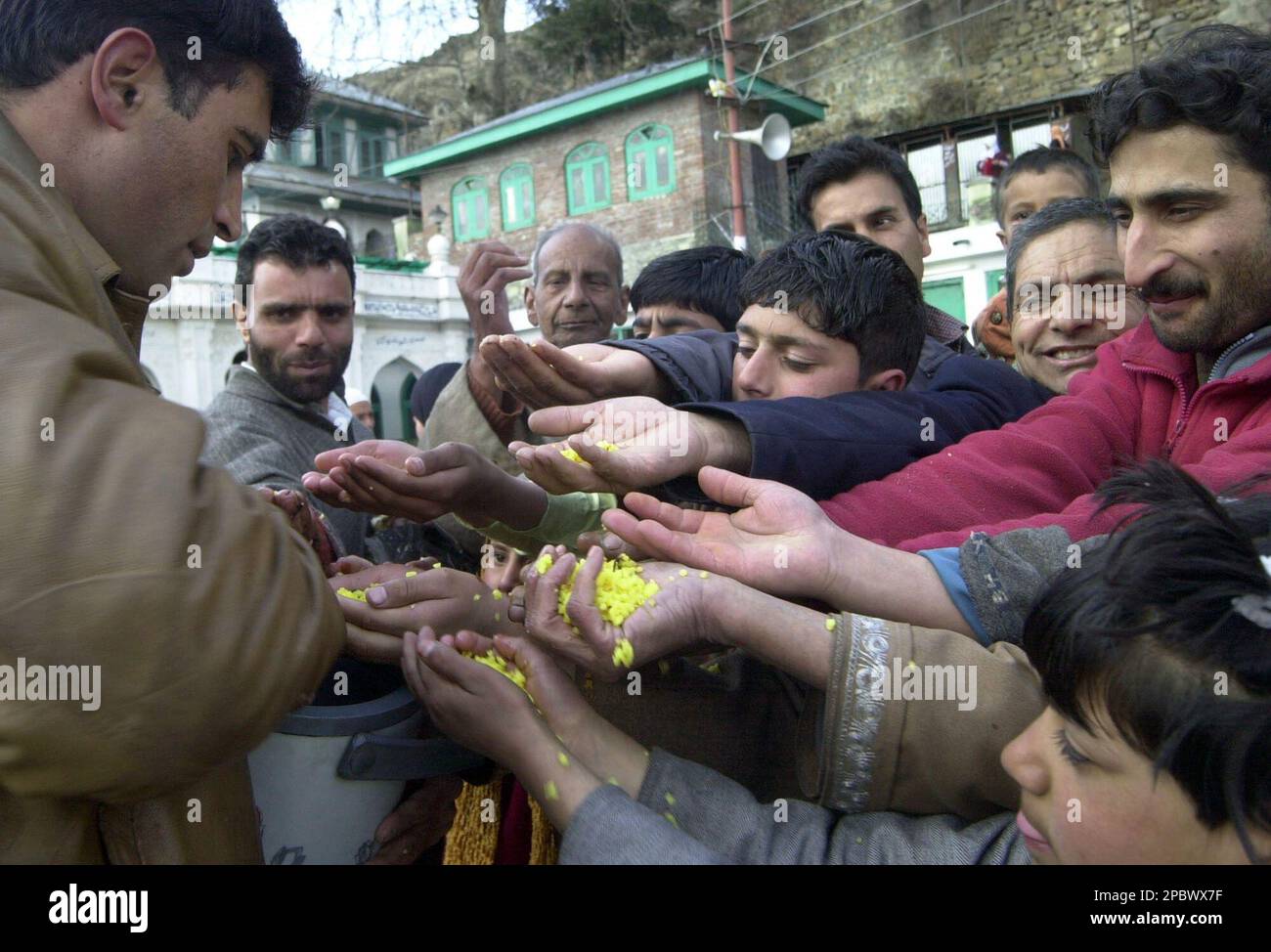 Kashmiri Muslim devotees receive colored rice offered by another ...