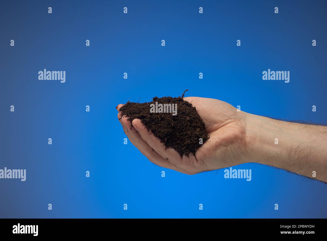 Pile of dark black earth soil held in hand by Caucasian male. Close up