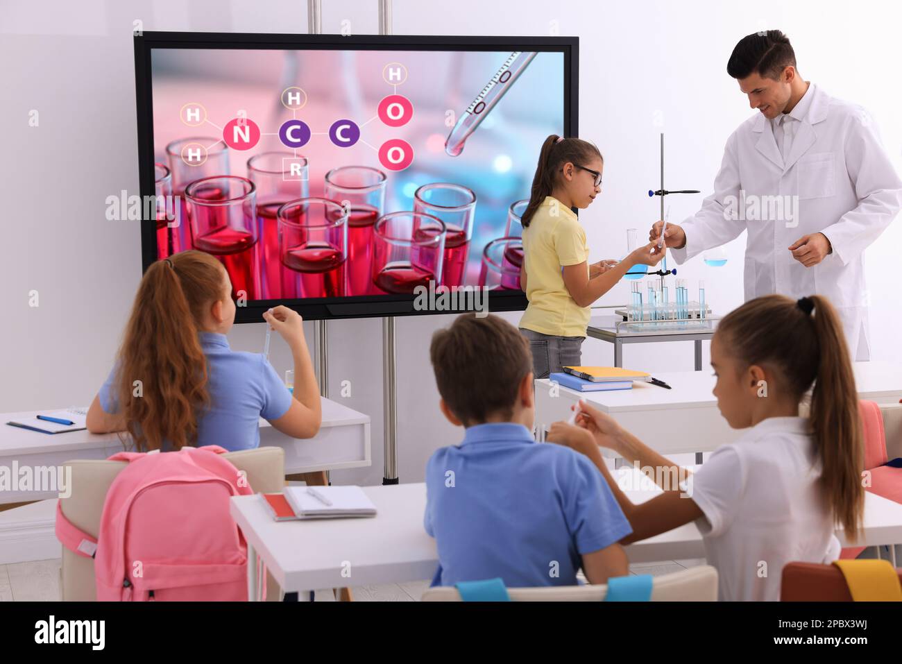 Teacher and pupils in classroom with interactive board during practical lesson Stock Photo