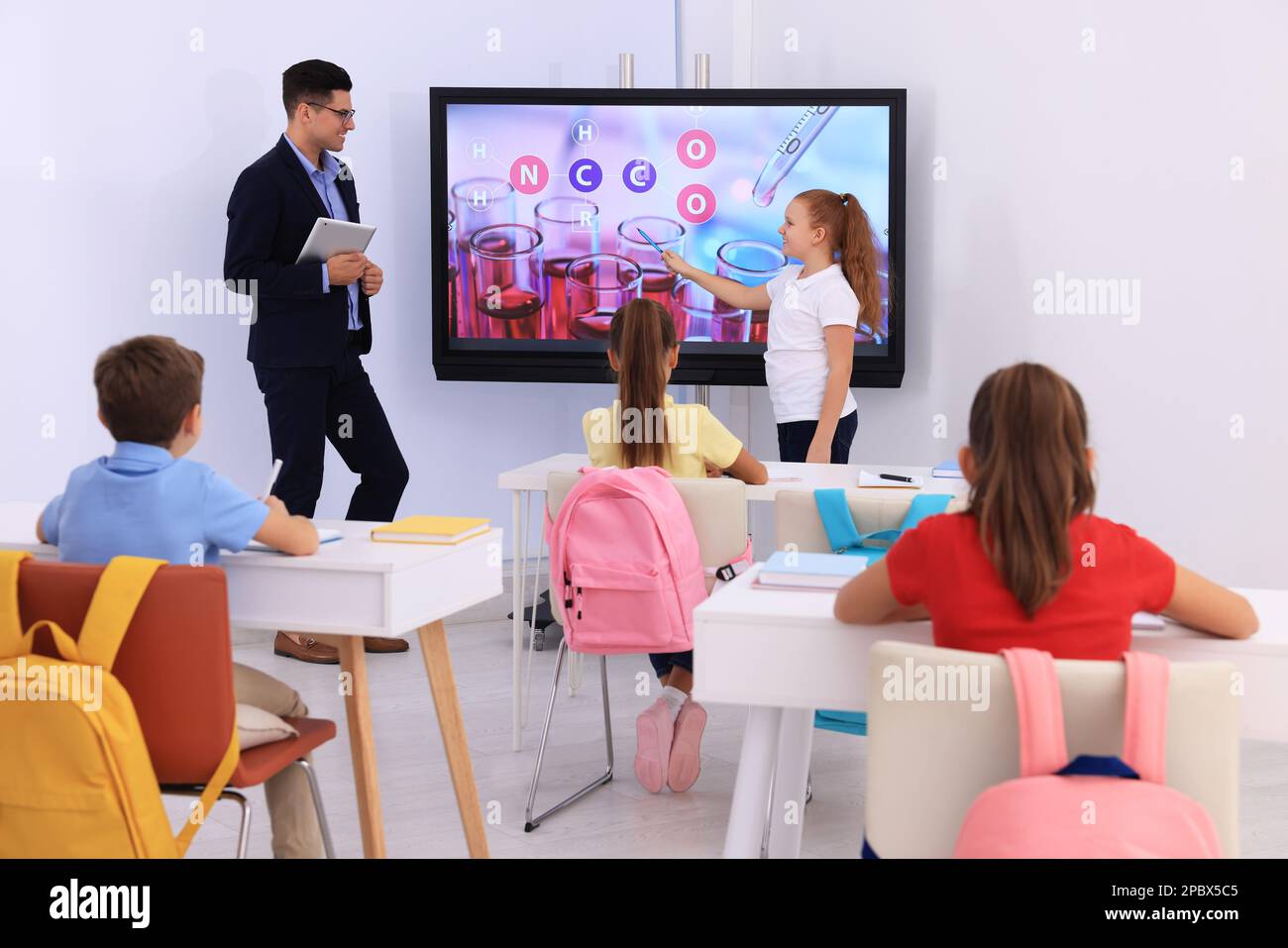 Teacher and pupil using interactive board in classroom during lesson Stock Photo