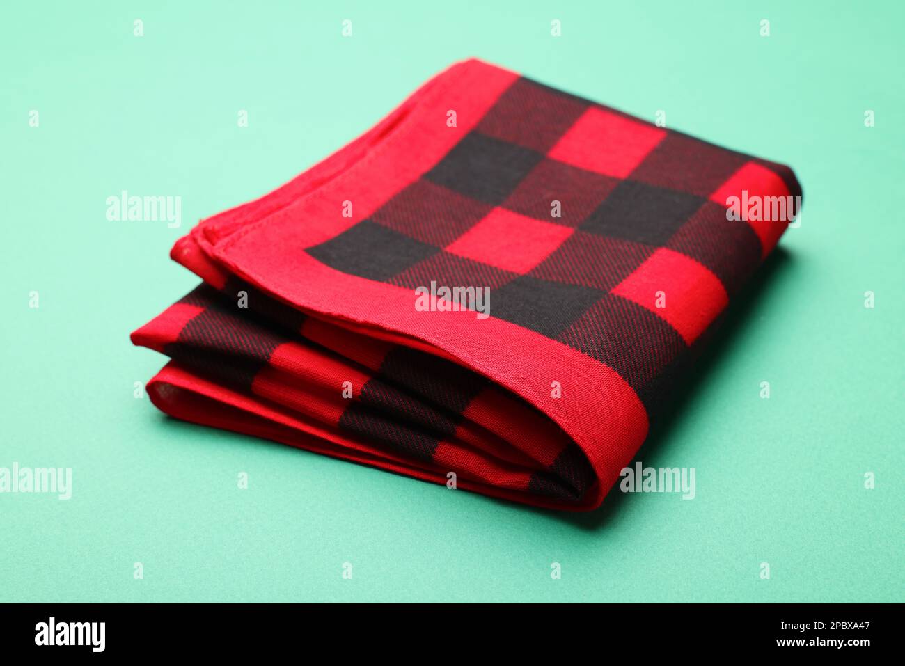 Folded red checkered bandana on turquoise background Stock Photo