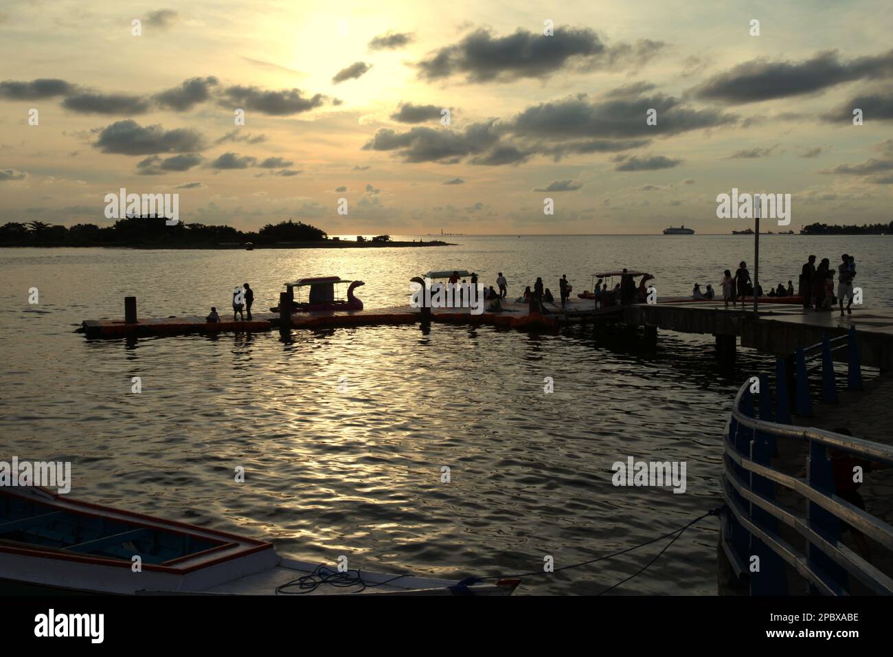 A jetty at Losari beach, a favourite beach for citizens to spend their afternoon leisure time in the coastal city of Makassar, South Sulawesi, Indonesia. One of the 30 coastal cities in Indonesia which is estimated to be potentially affected by the rising sea level, Makassar has been considered by researchers and scientists as a city with significant environmental and social problems, mainly as results of the geomorphological condition and the policy on land use and coastal development, in particularly the reclamation projects currently conducted by the provincial governments. Stock Photo
