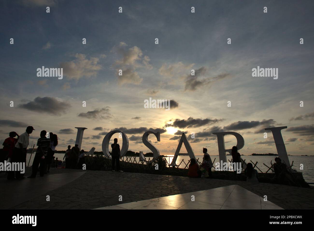 Citizens and tourists are having an afternoon leisure time at the recreational platform of Losari beach in the coastal area of Makassar City, South Sulawesi, Indonesia. One of the 30 coastal cities in Indonesia which is estimated to be potentially affected by the rising sea level, Makassar has been considered by researchers and scientists as a city with significant environmental and social problems, mainly as results of the geomorphological condition and the policy on land use and coastal development, in particularly the reclamation projects currently conducted by the provincial governments. Stock Photo